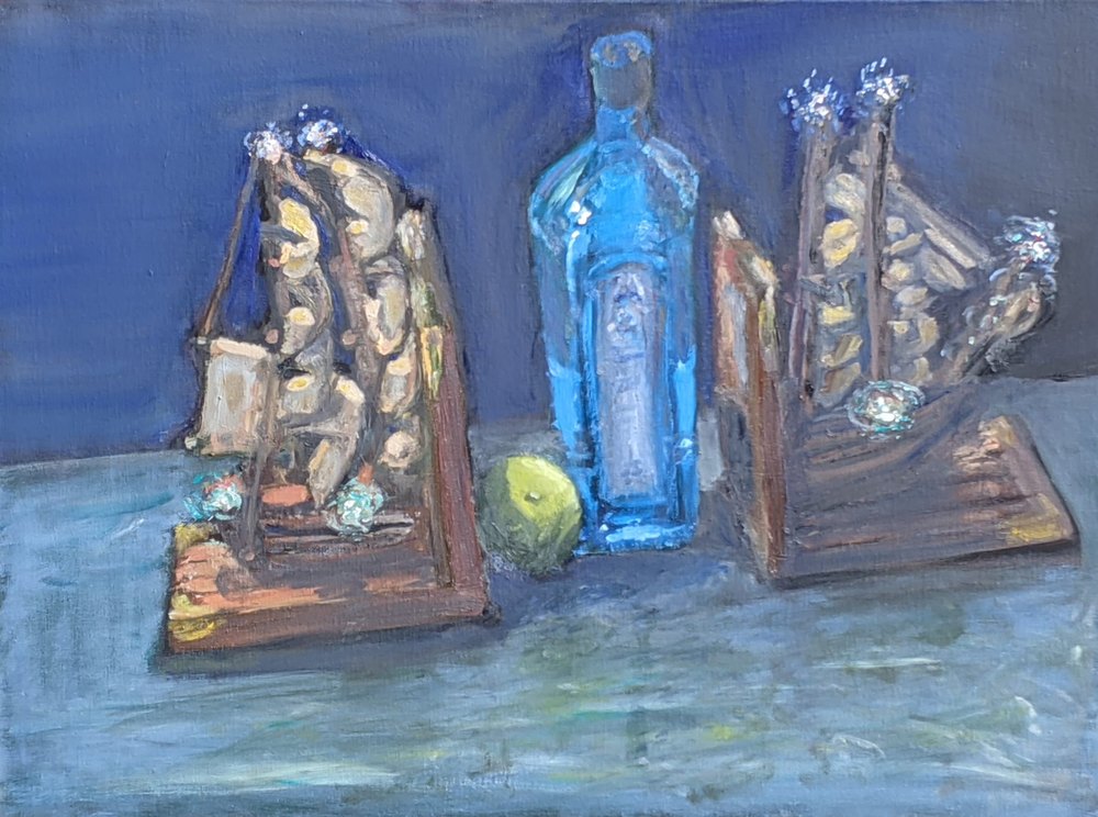 Two model sailing ships flanking a blue bottle and a lime, on a blue-green ground